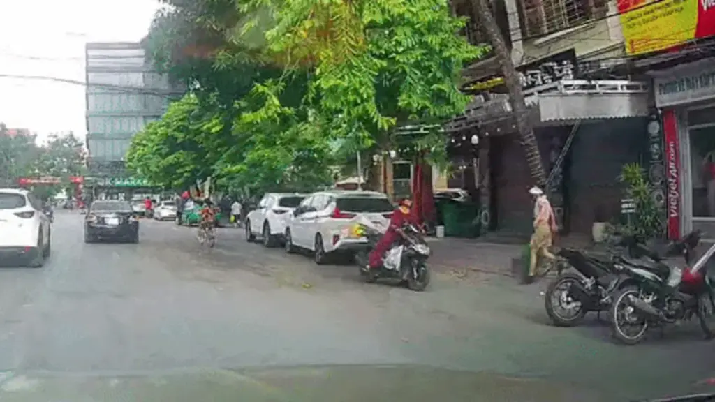 Người phụ nữ lao đầu vào ôtô để nhặt quả xoài rụng